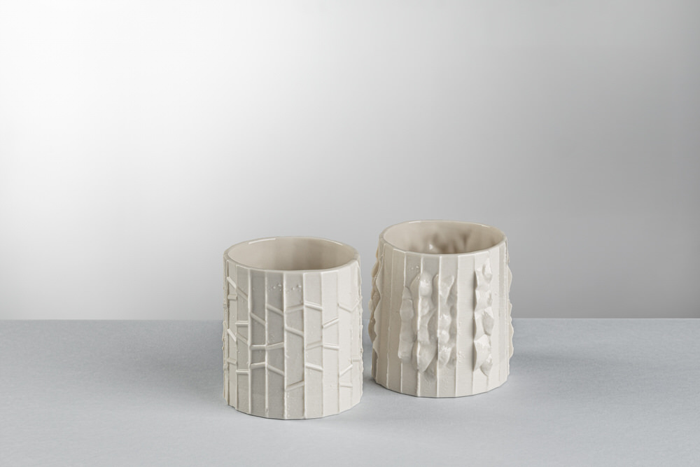 Due vasi cilindrici in ceramica bianca con superfici a rilievo, still life di prodotto su fondo neutro