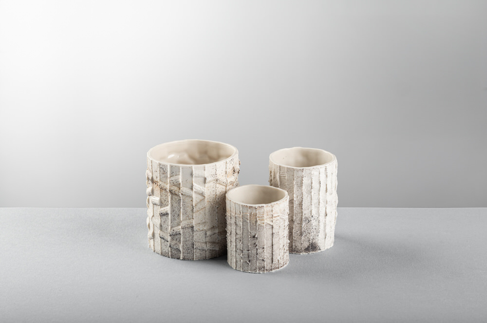 Tre vasi cilindrici in ceramica di altezze diverse, superficie ruvida e interni smaltati